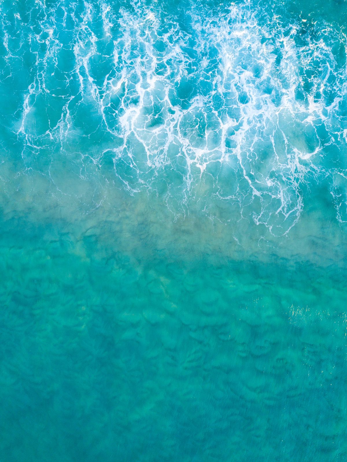 Aerial view of turquoise ocean waves and surf
